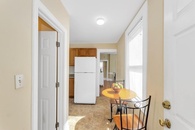 kitchen with brown cabinets, freestanding refrigerator, and light tile patterned flooring