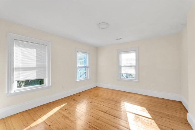 empty room with visible vents, baseboards, and hardwood / wood-style floors