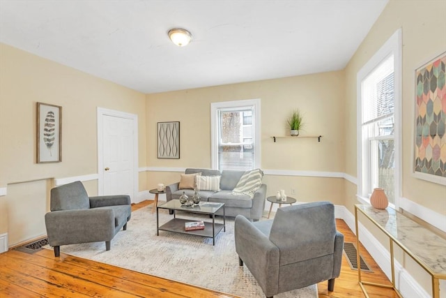 living room with wood finished floors, baseboards, visible vents, and a healthy amount of sunlight