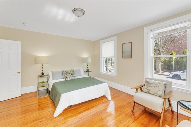 bedroom with light wood-type flooring, baseboards, and multiple windows
