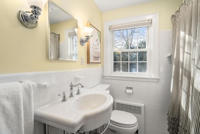 bathroom featuring tile walls, radiator, sink, and toilet