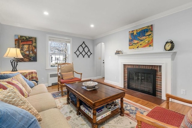 living room with ornamental molding, radiator heating unit, a fireplace, and wood-type flooring