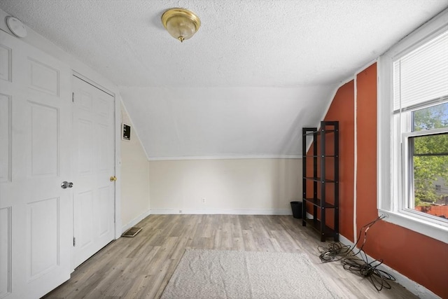 bonus room featuring a textured ceiling, wood finished floors, lofted ceiling, and baseboards