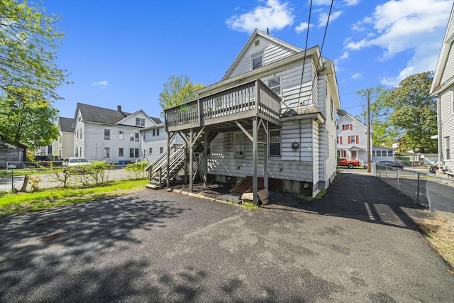 back of property with fence, a deck, and a residential view