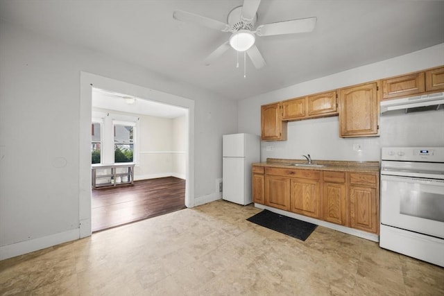 kitchen with under cabinet range hood, white appliances, a sink, and baseboards