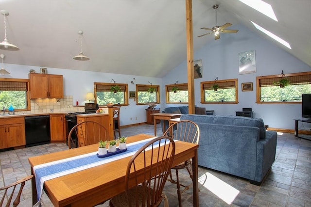 dining space with high vaulted ceiling, a skylight, baseboards, a ceiling fan, and stone tile flooring