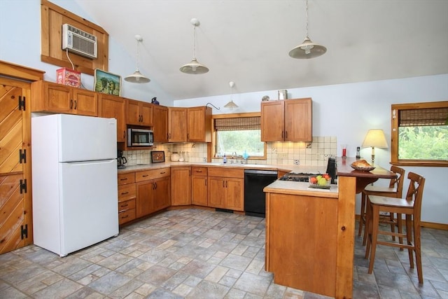 kitchen featuring light countertops, dishwasher, stainless steel microwave, a wall unit AC, and freestanding refrigerator