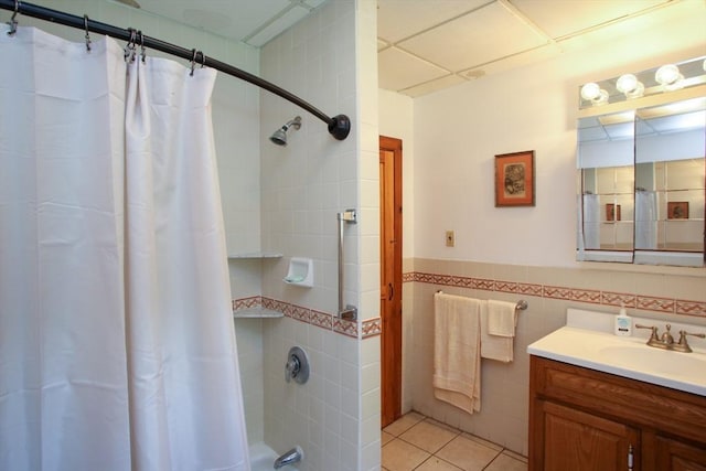 bathroom with tile walls, vanity, wainscoting, tile patterned flooring, and shower / bath combination with curtain