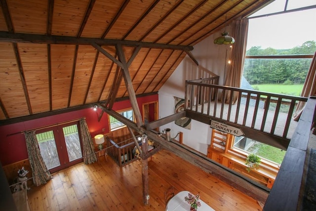 unfurnished living room featuring high vaulted ceiling, beam ceiling, hardwood / wood-style floors, french doors, and wood ceiling