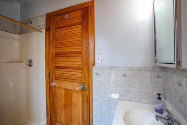 full bath with tile walls, a sink, and a shower