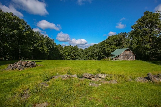 view of yard featuring an outbuilding, a wooded view, and a barn
