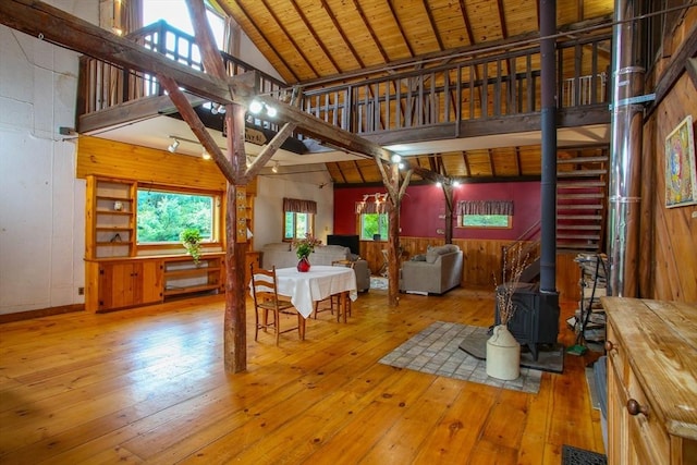 living area with hardwood / wood-style floors, visible vents, wood walls, and a wood stove