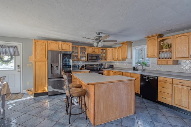 kitchen featuring appliances with stainless steel finishes, a center island, sink, backsplash, and a breakfast bar area