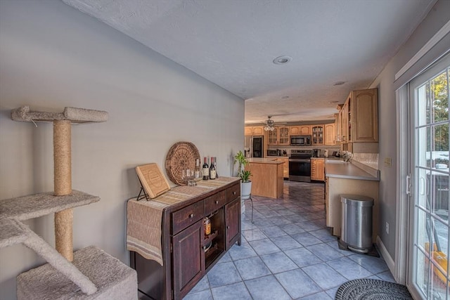 kitchen with kitchen peninsula, appliances with stainless steel finishes, sink, light tile patterned flooring, and a center island