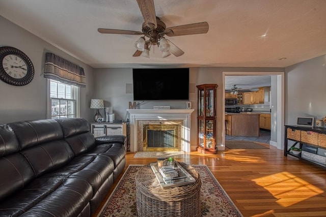 living room with ceiling fan, light hardwood / wood-style flooring, and a fireplace