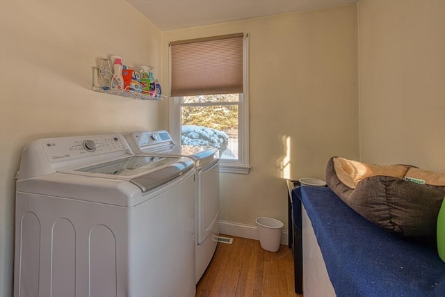 clothes washing area featuring light wood-type flooring and washer and clothes dryer