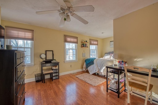 bedroom with multiple windows, light hardwood / wood-style flooring, and ceiling fan