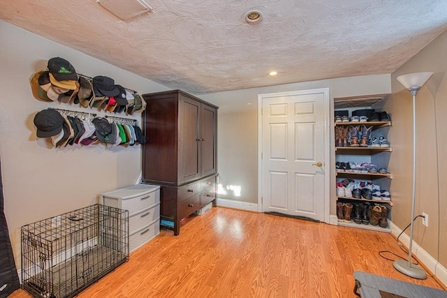 mudroom with light wood-type flooring and a textured ceiling