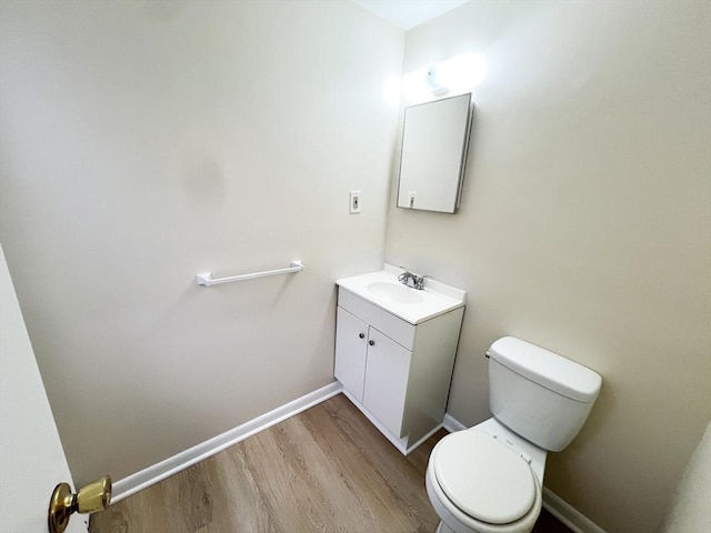bathroom featuring vanity, baseboards, wood finished floors, and toilet