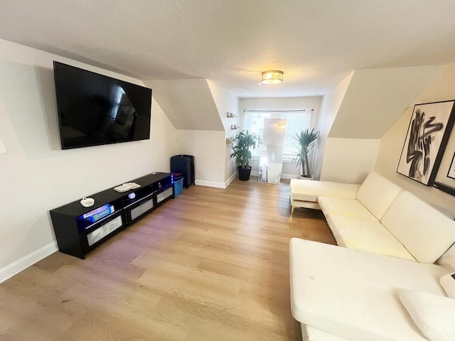 living area with baseboards, light wood-type flooring, and lofted ceiling