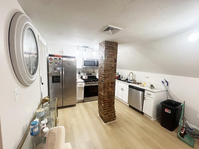 kitchen featuring decorative columns, stainless steel appliances, light wood-style flooring, and visible vents