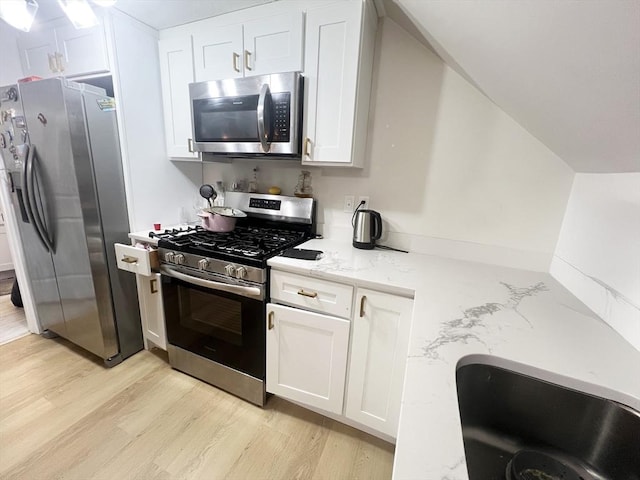 kitchen featuring light wood-style floors, light stone countertops, stainless steel appliances, and white cabinetry