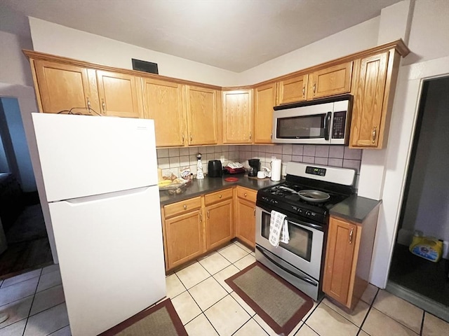 kitchen with dark countertops, appliances with stainless steel finishes, decorative backsplash, and light tile patterned floors