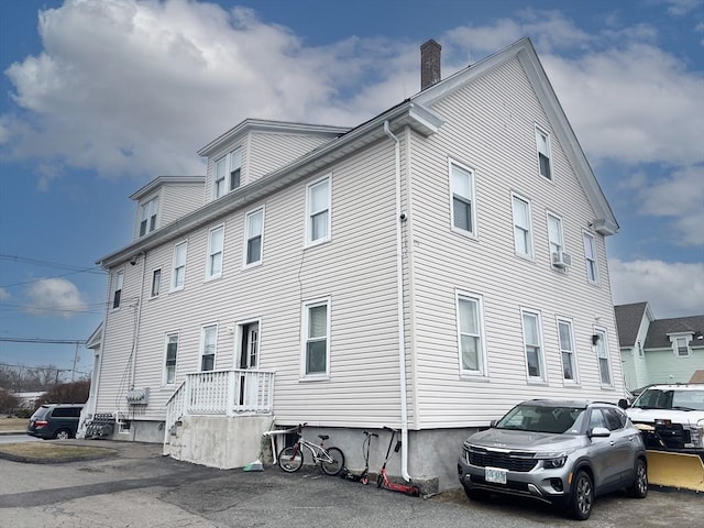 view of home's exterior with a chimney and cooling unit