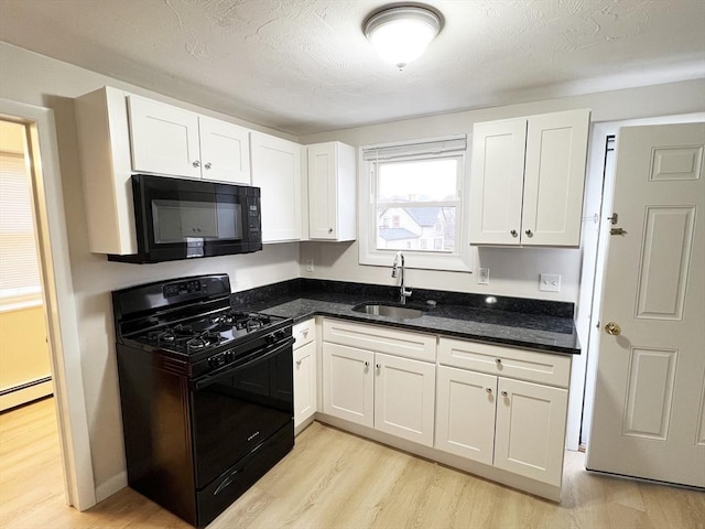 kitchen featuring light wood-style flooring, white cabinetry, a sink, and black appliances