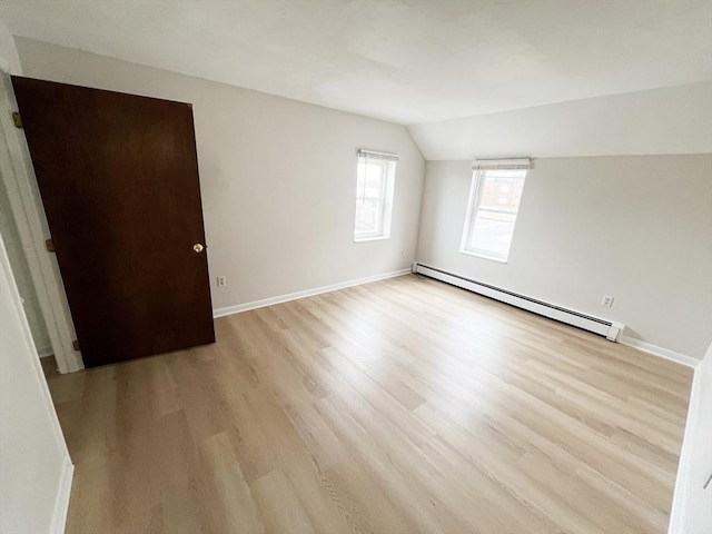 unfurnished room with baseboards, vaulted ceiling, light wood-style flooring, and a baseboard radiator