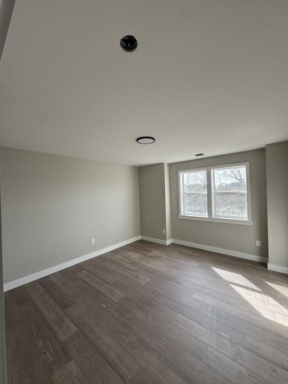 spare room with baseboards and dark wood finished floors