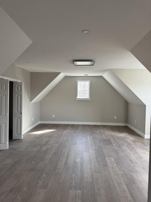 additional living space with baseboards, lofted ceiling, and wood finished floors