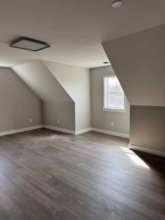 additional living space featuring vaulted ceiling, visible vents, baseboards, and wood finished floors