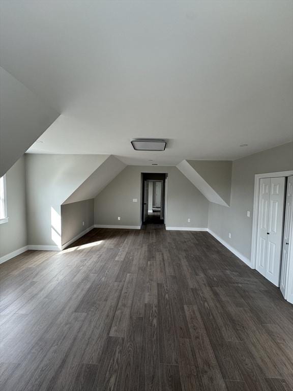 bonus room featuring lofted ceiling, baseboards, and dark wood-style flooring