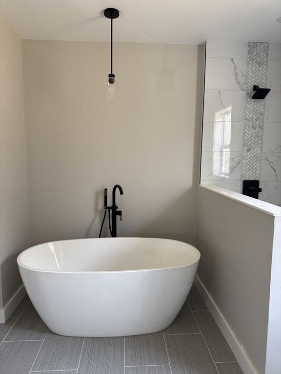 full bath with tiled shower, baseboards, and a soaking tub