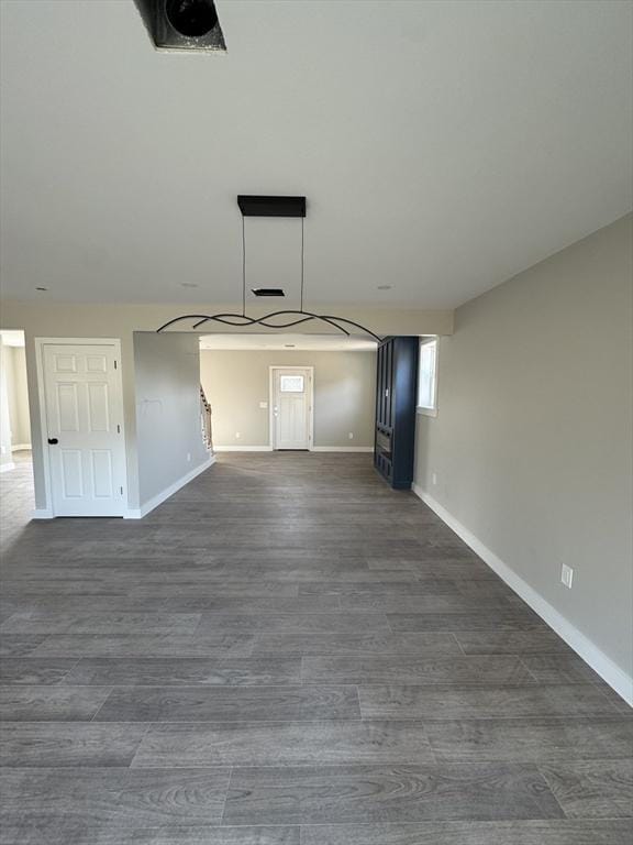 spare room with baseboards and dark wood-style floors