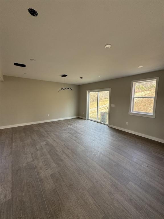 empty room with dark wood-type flooring and baseboards