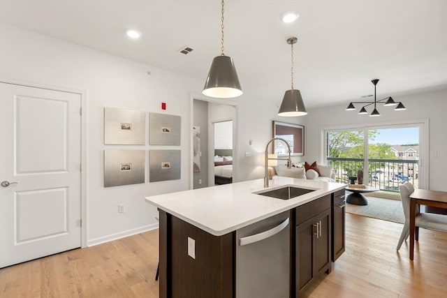 kitchen with dishwasher, decorative light fixtures, sink, a center island with sink, and dark brown cabinets