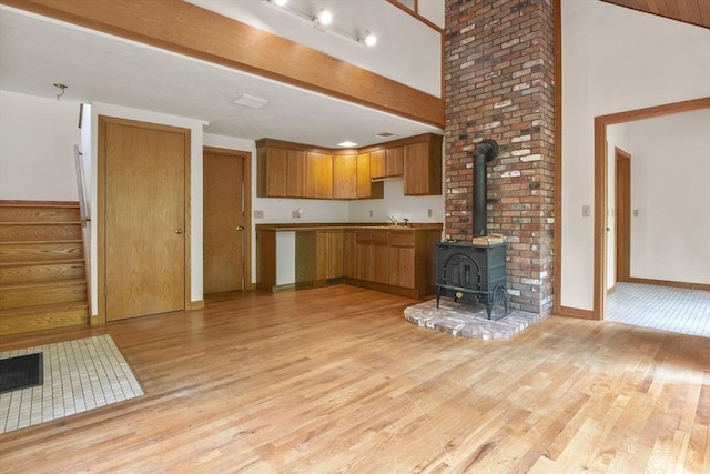 4 Fiske Mill Rd, Upton, MA 01568 - kitchen featuring light wood-style flooring, brown cabinets, a wood stove, baseboards, and a sink
