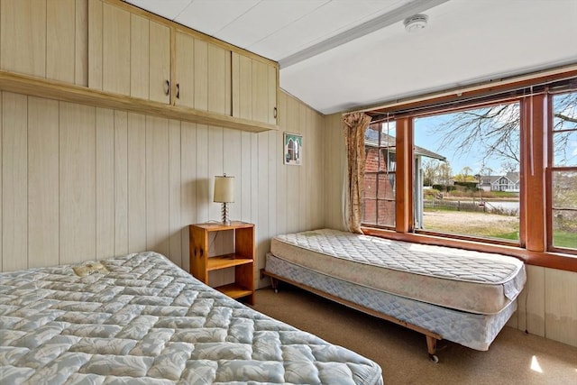 carpeted bedroom featuring wooden walls and vaulted ceiling