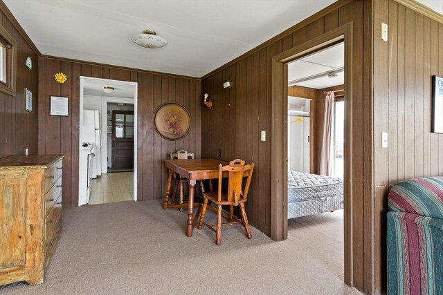 dining area with light colored carpet and wooden walls