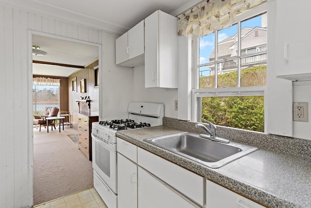 kitchen with white cabinetry, light carpet, white range with gas stovetop, and a sink