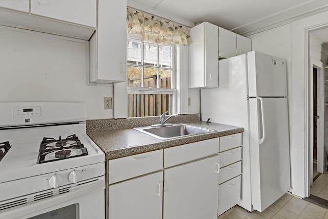 kitchen with dark countertops, white cabinetry, white appliances, and a sink