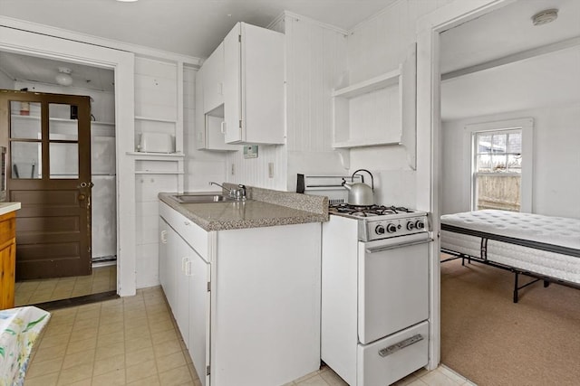 kitchen with white range with gas stovetop, a sink, white cabinets, and open shelves
