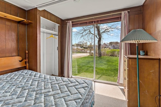 carpeted bedroom featuring wood walls and access to exterior