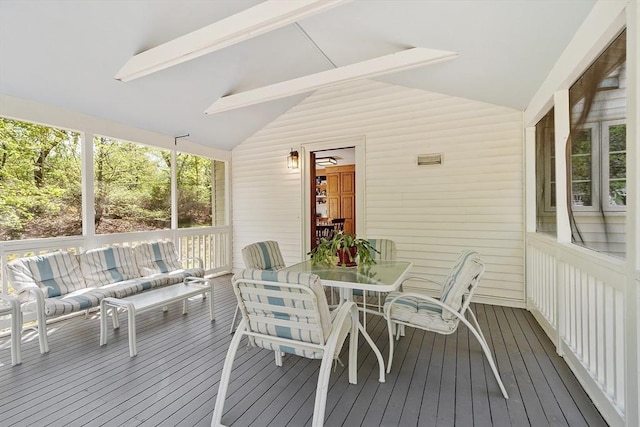 sunroom featuring beamed ceiling, outdoor lounge area, and outdoor dining space
