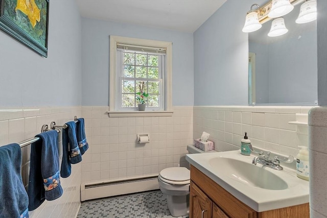 bathroom featuring tile walls, baseboard heating, wainscoting, vanity, and toilet
