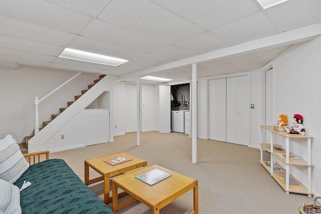 living room featuring stairs, light colored carpet, washer and clothes dryer, and a paneled ceiling