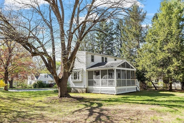 rear view of property featuring a yard and a sunroom
