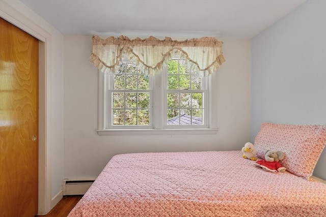 bedroom with dark wood-style flooring and baseboard heating